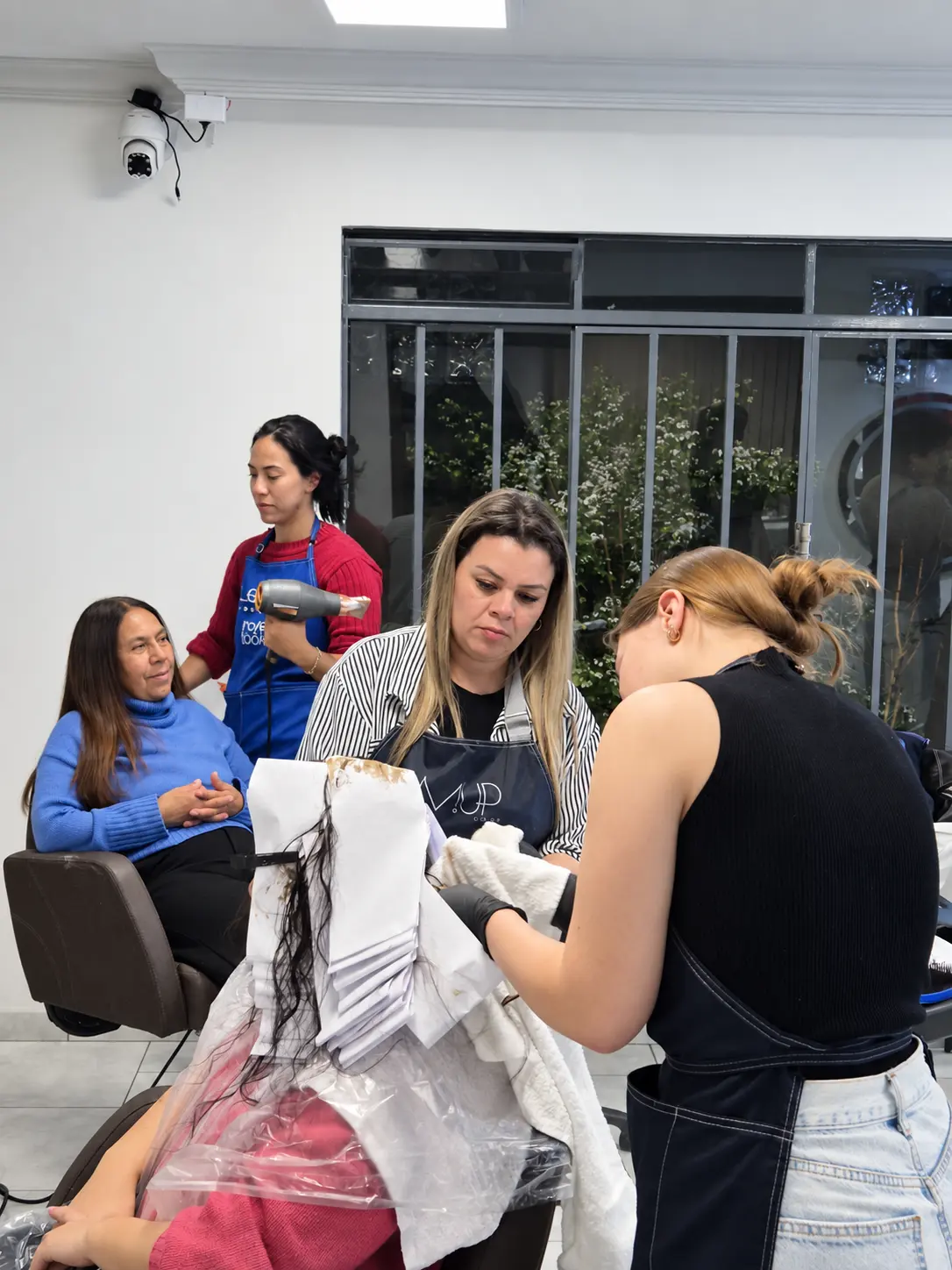 Profissionais praticando uma técnica de cabelo com acompanhamento na FENIÉ Academy