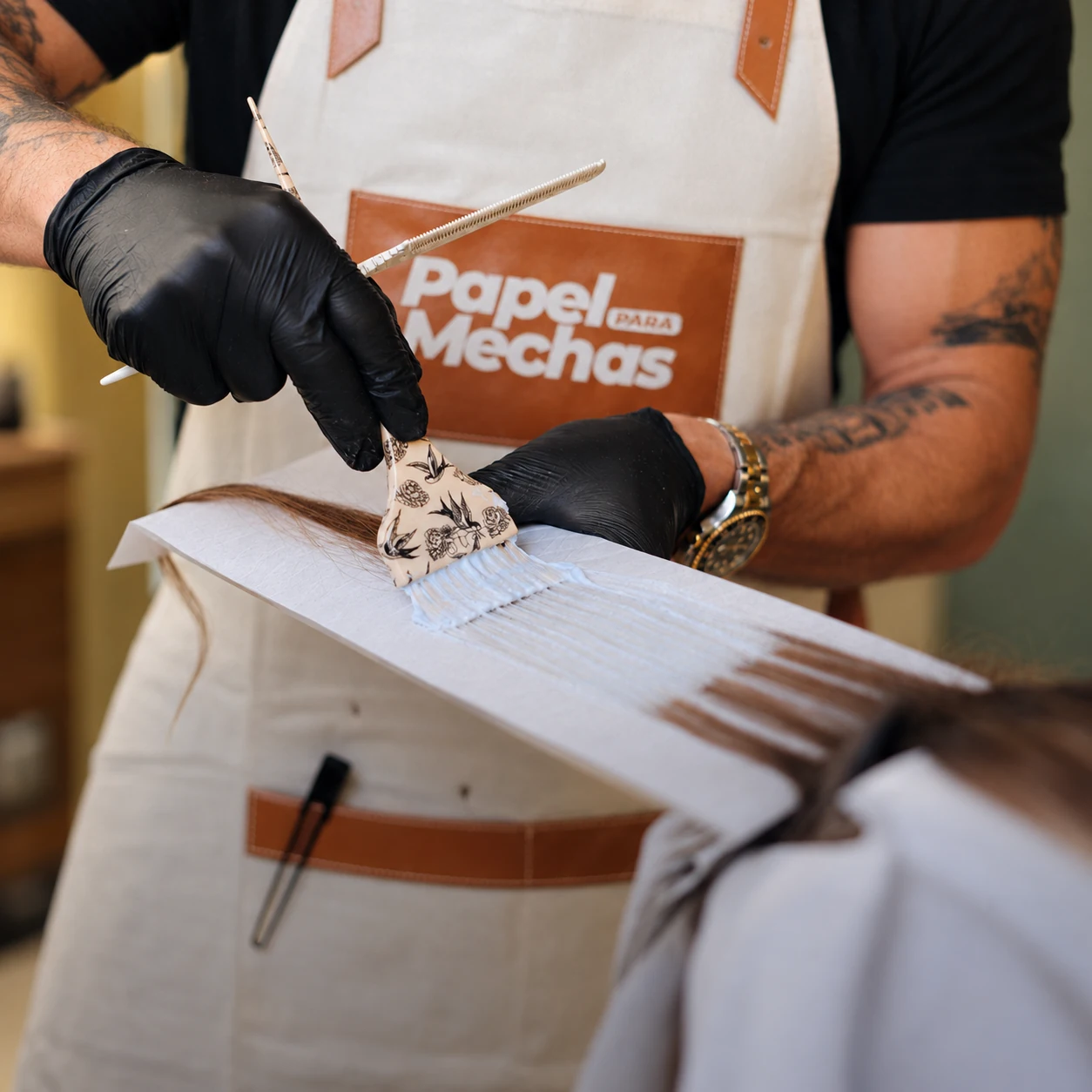 Mãos de profissional aplicando descolorante sobre mechas apoiadas em papel